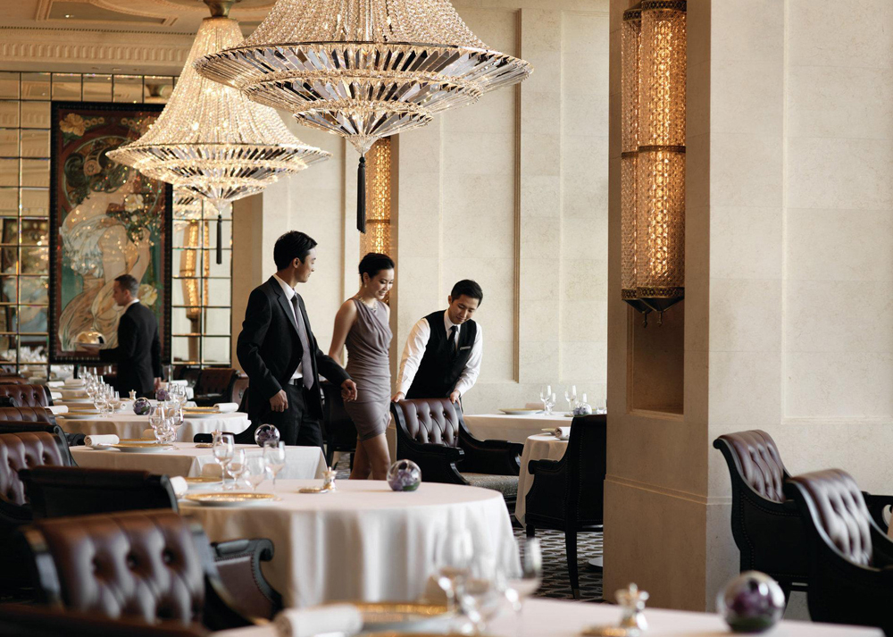 Muž a žena usedají k pracovnímu obědu v hotelu Four Seasons Hong Kong.
